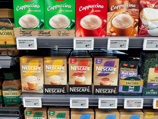 Coffee products on supermarket shelves with small electronic price labels along the shelf edges.