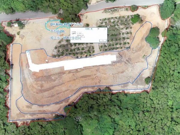 Aerial view of a cleared hillside site with outlined survey areas, surrounded by forest and next to a road.