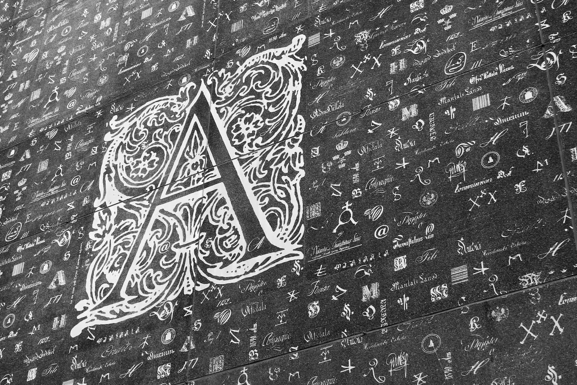 Image of the facade of the National Archives of Finland depicting letters of alphabets and various symbols which are archived in the building.