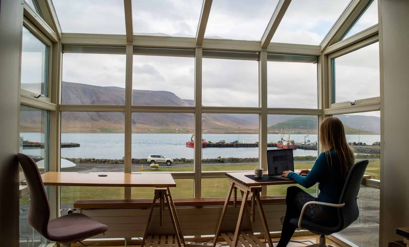 A woman sitting alone at a desk overlooking a remote landscape.