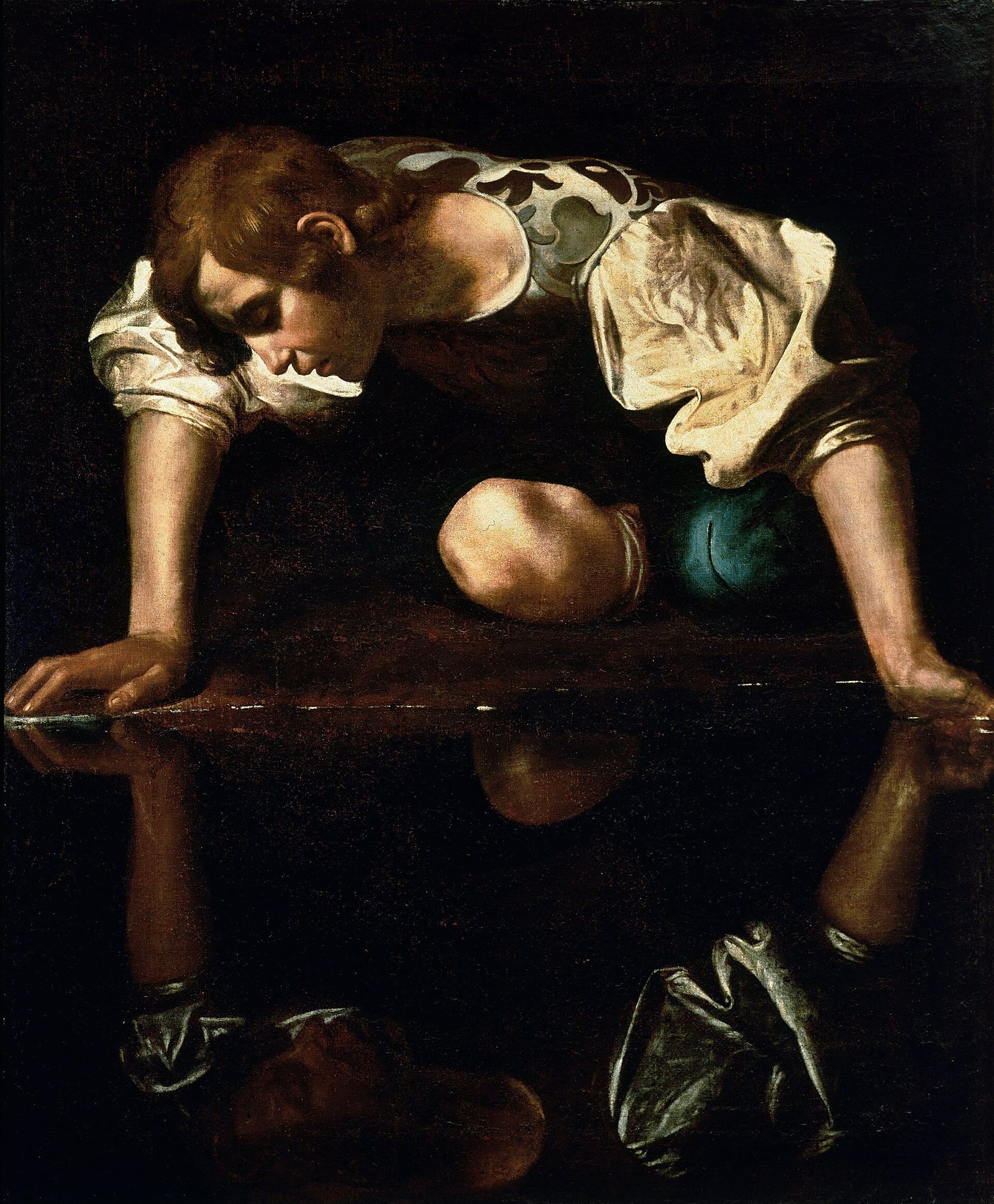 A young man leans over dark water, transfixed by his reflection, illuminated against a deep shadowed background.