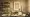An artistic and inviting library setting with a desk featuring an open laptop, a cup of coffee, a crystal tumbler of whisky,