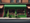 AI generated image of a shop front with a green awning, which contrasts with the drab awning of the shops on either side.