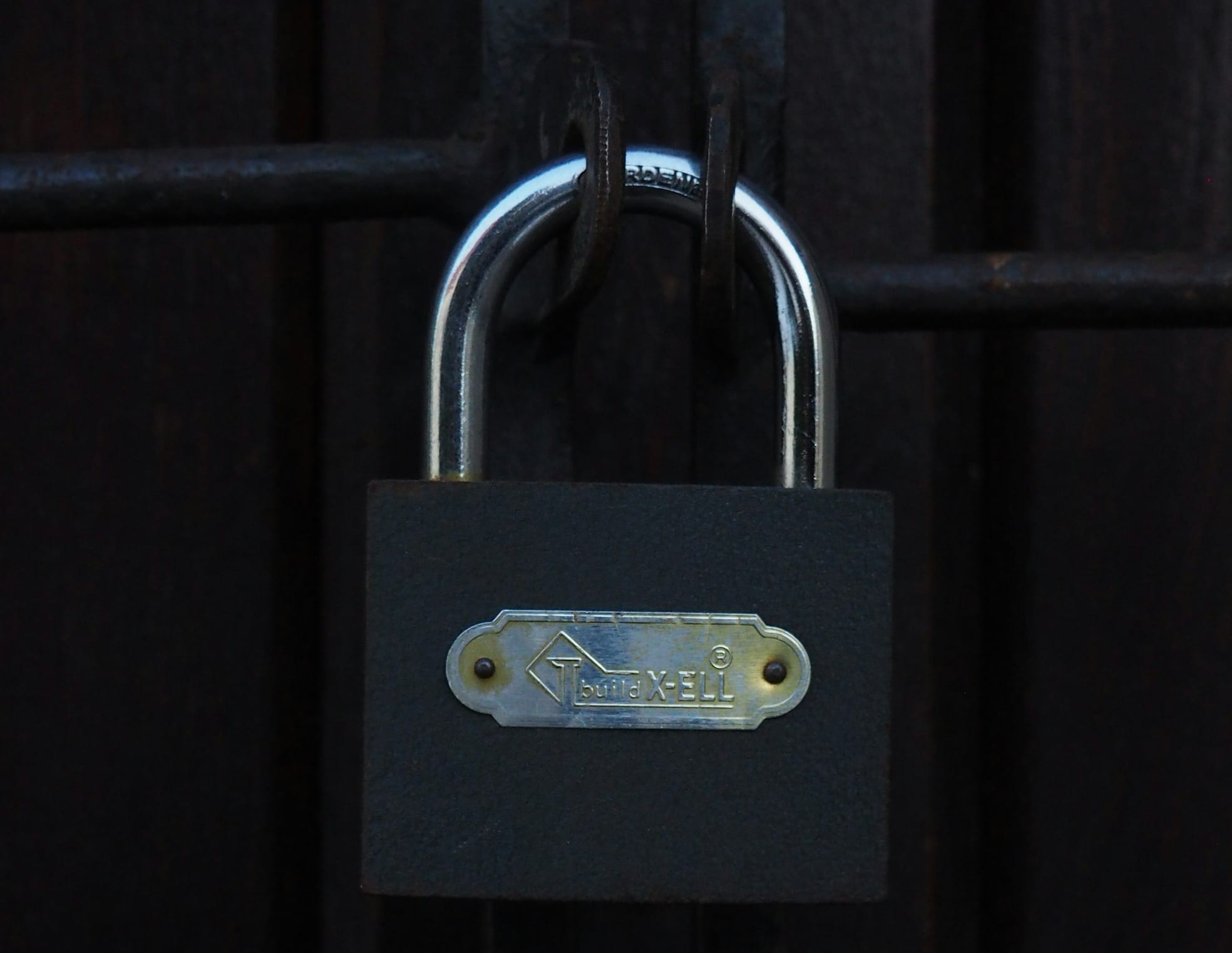 A metal padlock securing a dark gate.