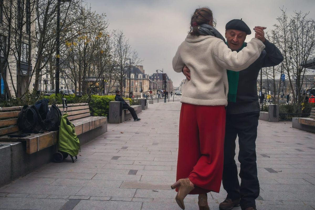 An older couple dancing tango on a city pavement