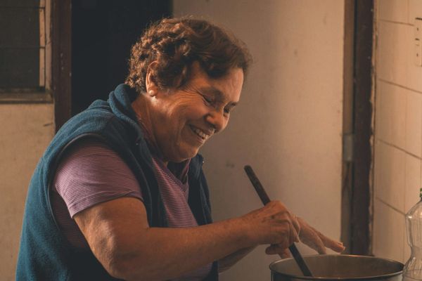 A smiling woman stirring a pot in a warm kitchen