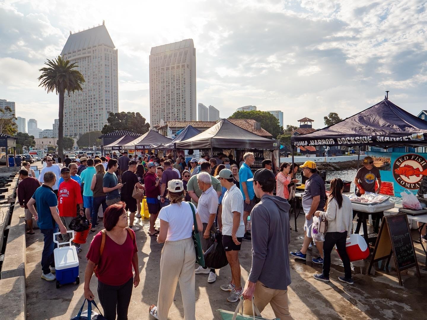 Large group of shoppers at an outdoor seafood marketplace.