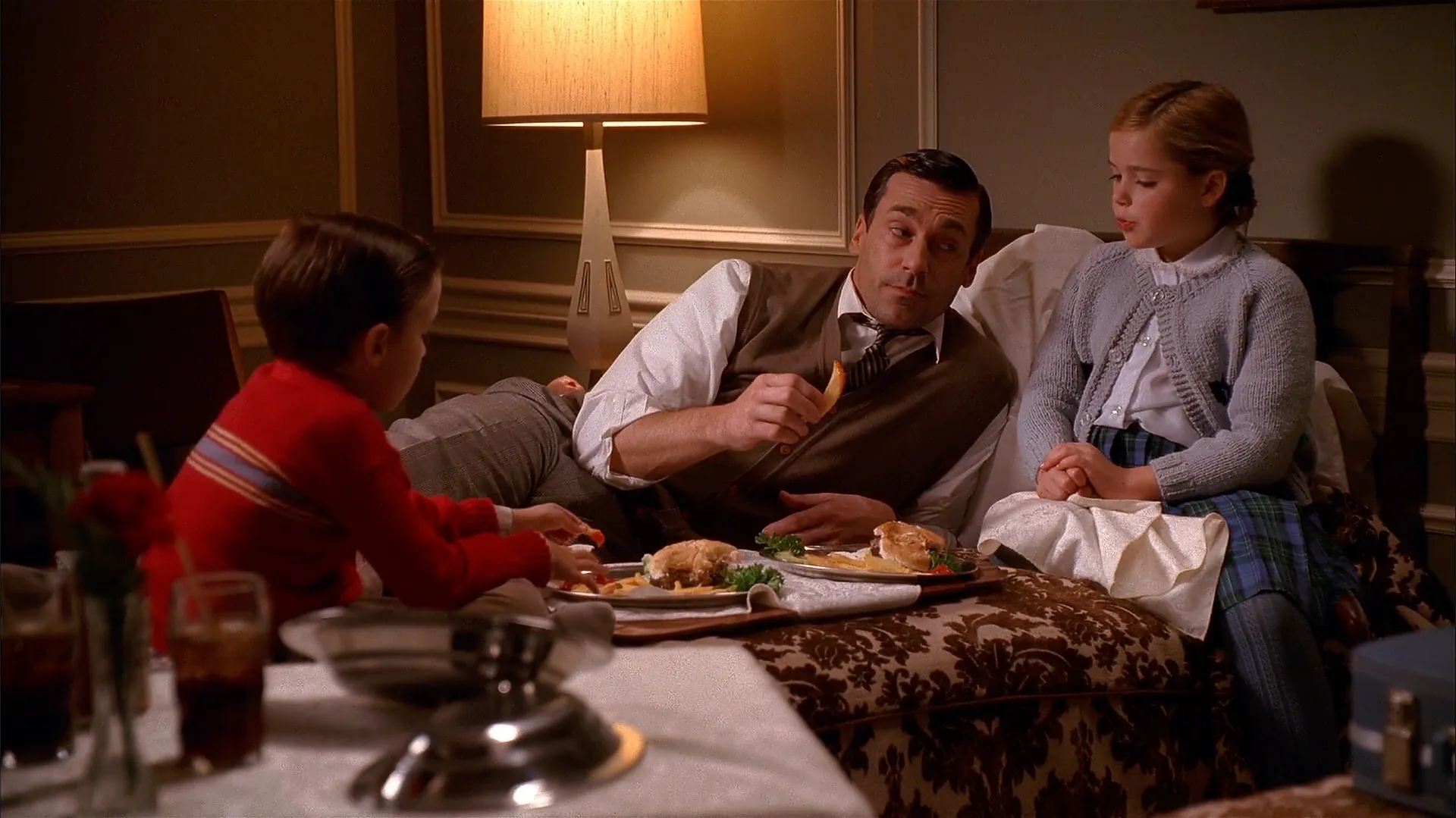 Don, Sally, and Bobby eating burgers and fries in bed.