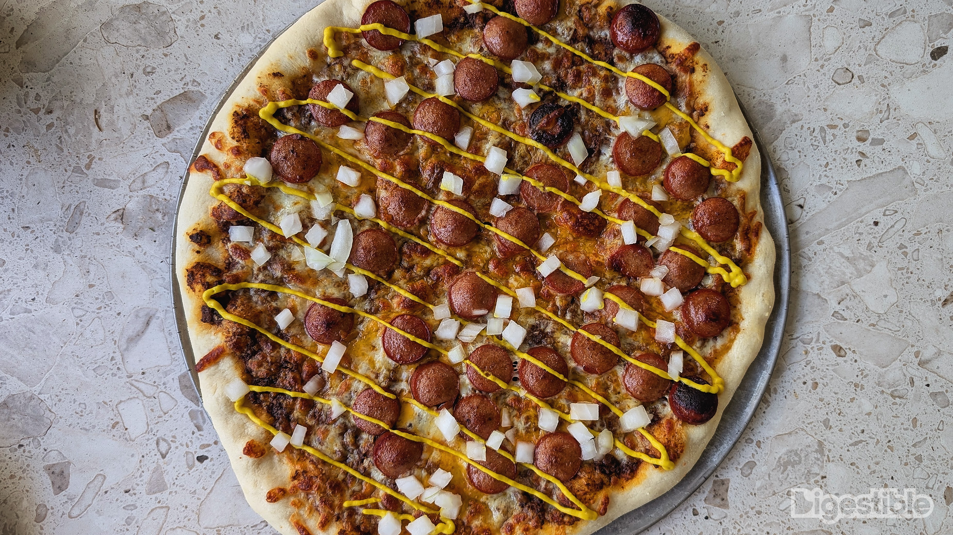 Hot dogs, chili, mustard, and onions on pizza.