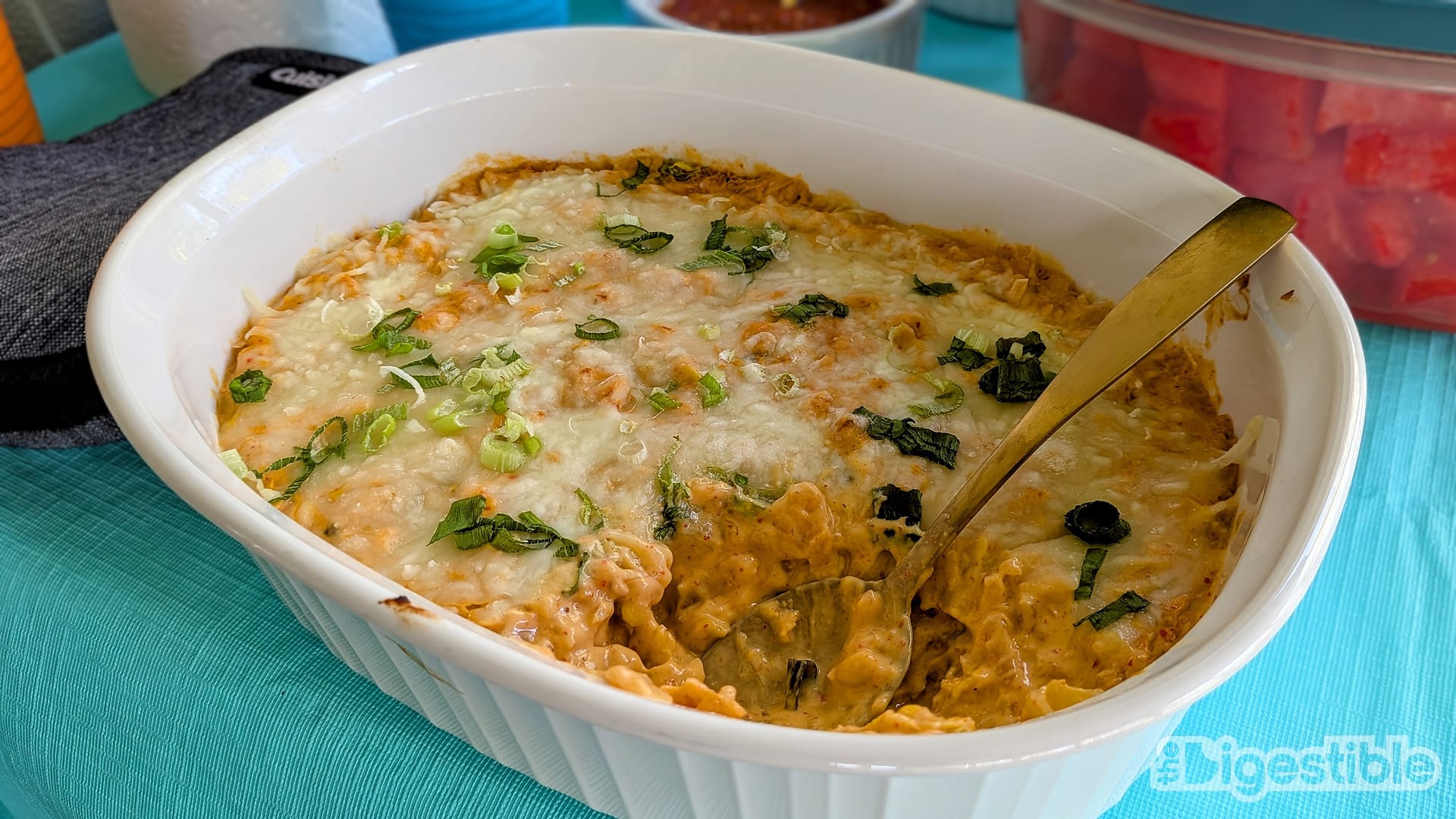 A casserole dish of kimchi corn queso on a picnic table.