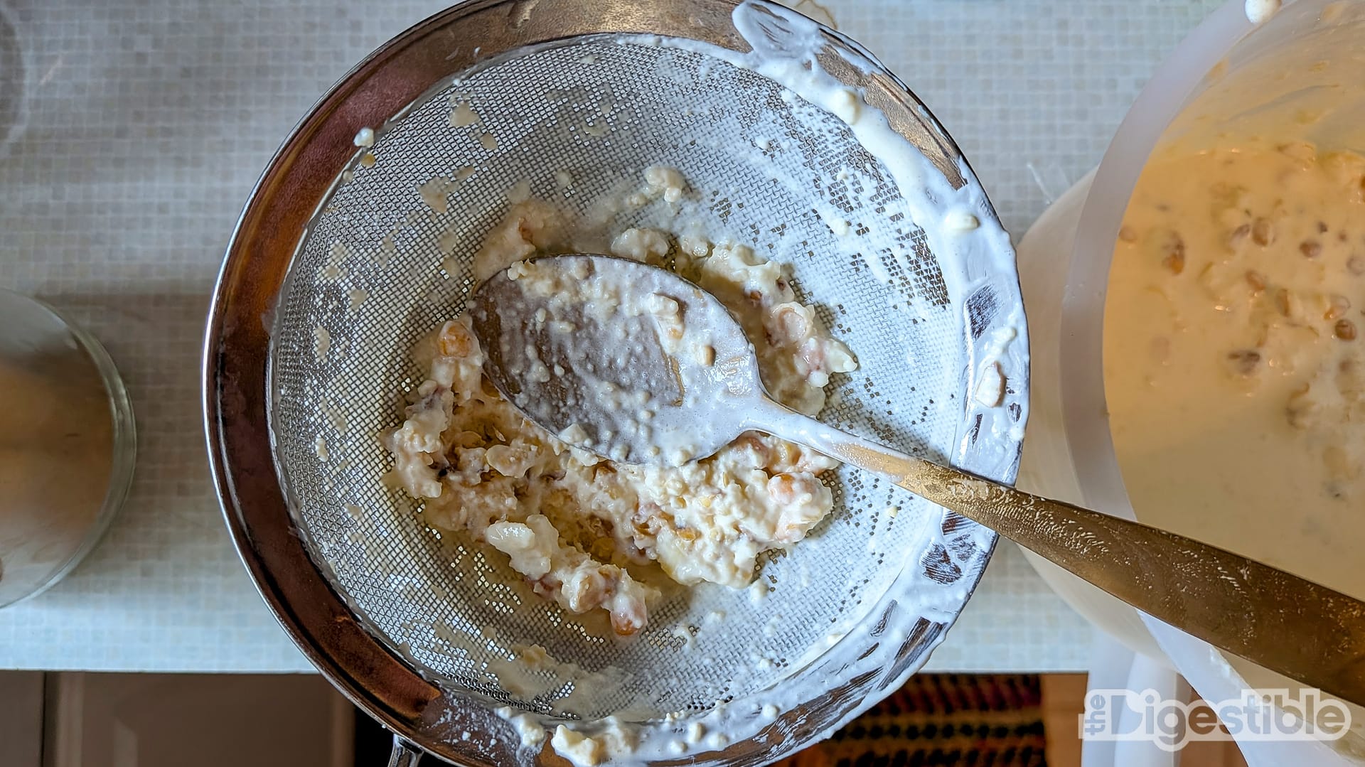 A spoon pushing popcorn mush through a strainer.
