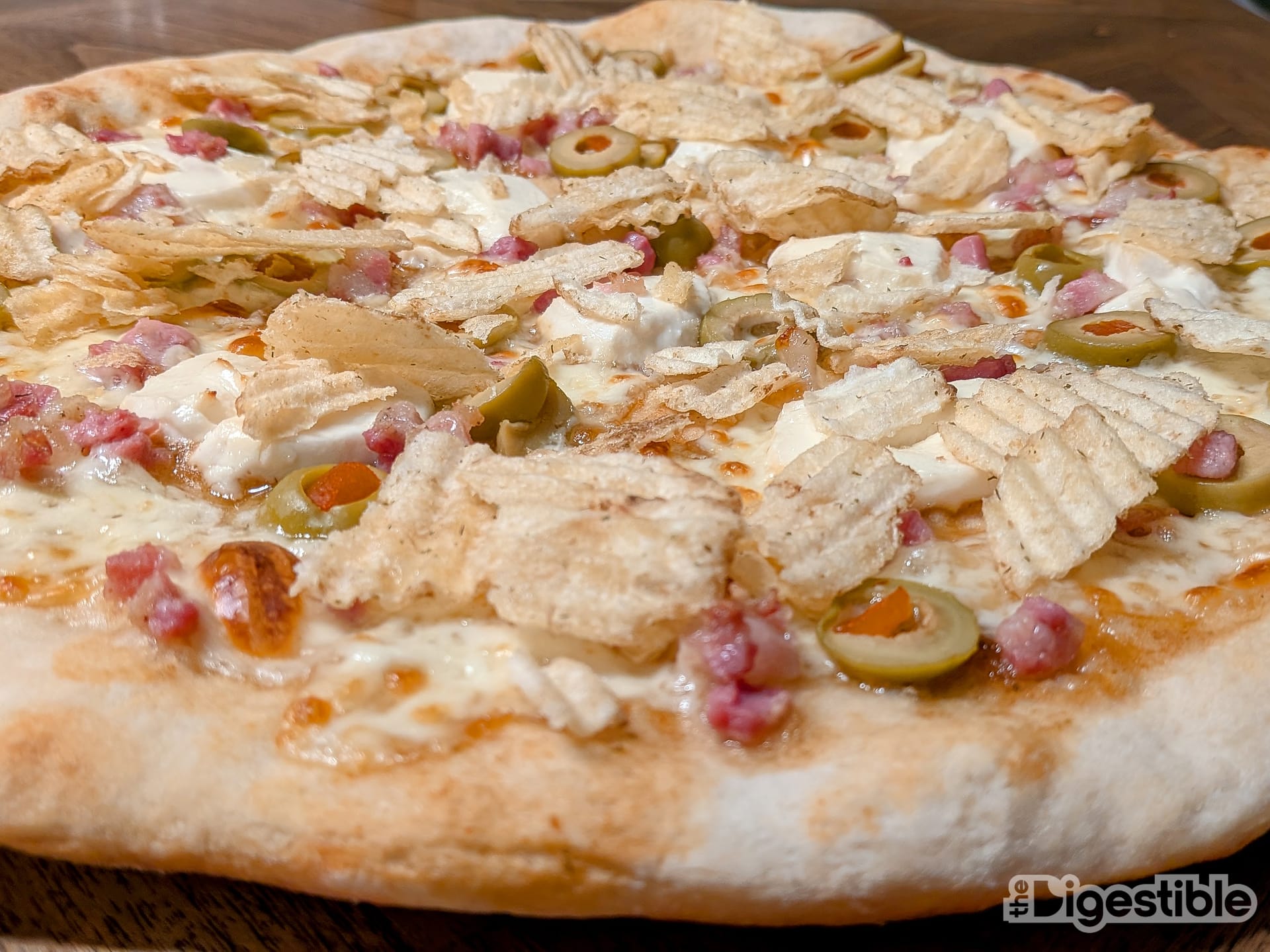 Potato chips, green olives, pancetta, and goat cheese on pizza.