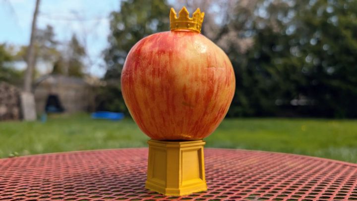 A honeycrisp apple on a pedestal wearing a crown.