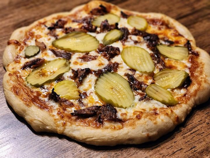 Pickles and rib meat on a pizza.