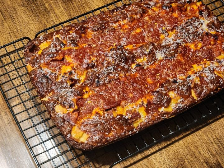 Bacon and pepperoni on a square deep dish pizza.