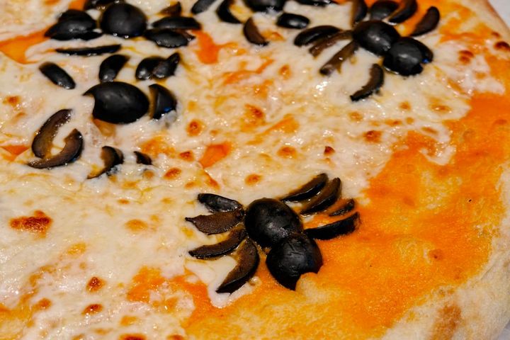 Olives in the shape of a spider on a pizza.