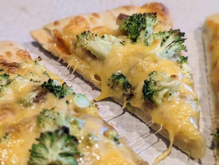 Broccoli and cheese on a pizza.