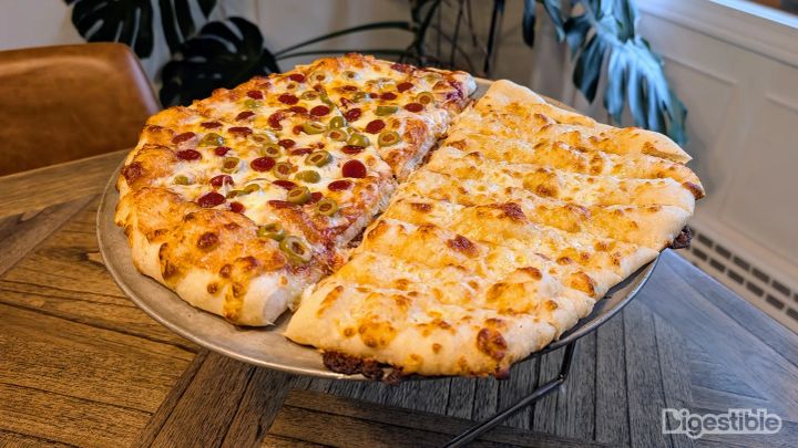 A pizza with breadsticks on one half.