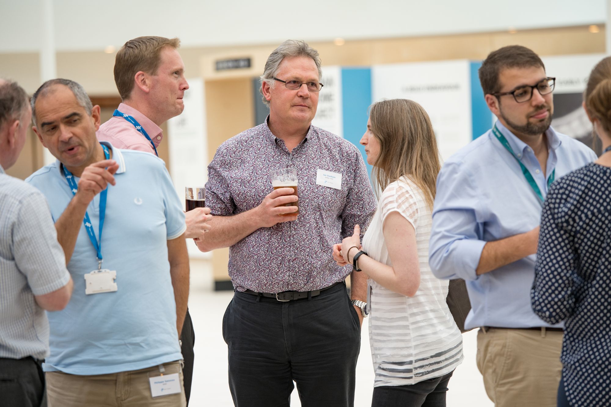 Several people in small group conversations standing, some holding drinks.