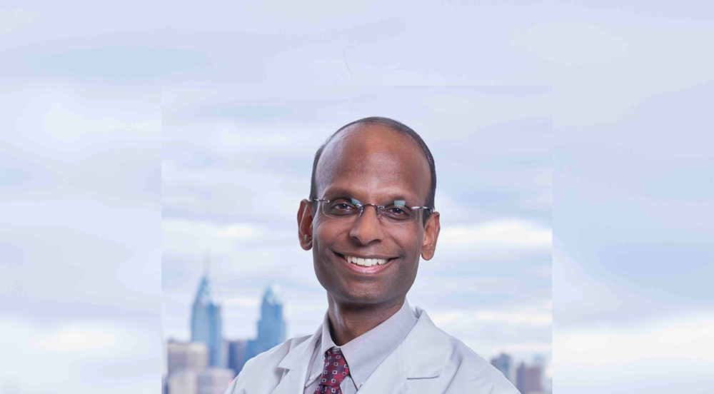 Photograph of Kiran Musunuru in front of the New York skyline. 