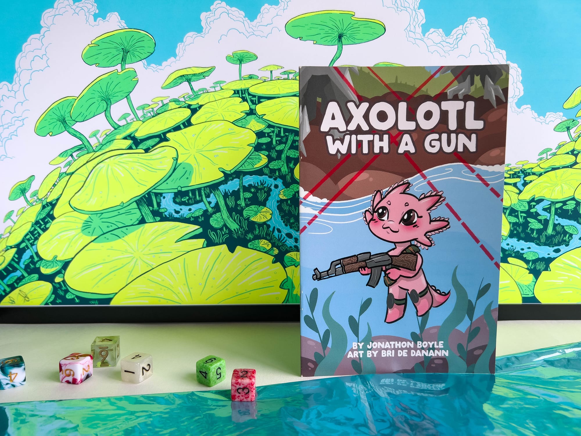 A product photo shot of Axolotl with a Gun. The zine cover shares the same art as the banner image in this article, and includes writing and art credits for Jon Boyle and Bri de Danann. Next to the zine is a small pile of 6-sided dice.