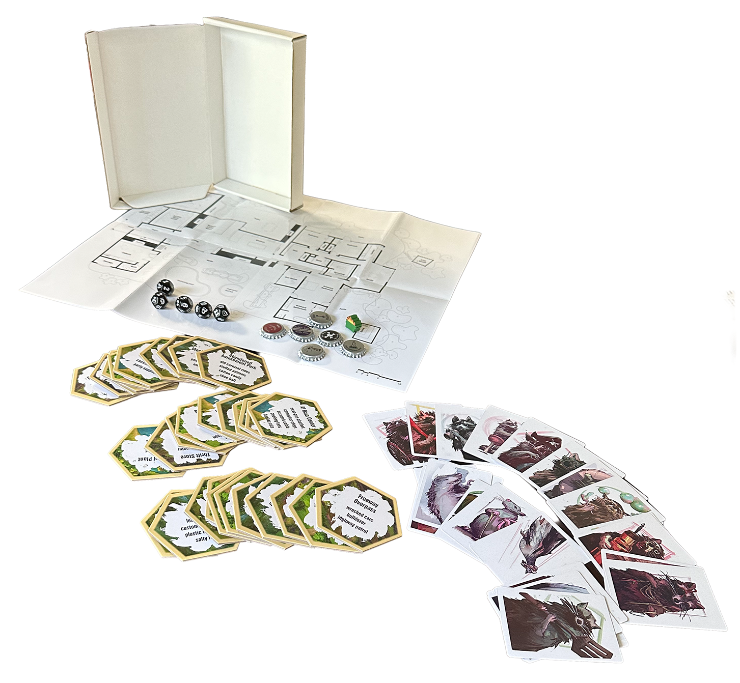 White mailer box with a large-format map, bottle caps, a dumpster-fire meeple, extra dice, hex tiles with white-out and type on them, and portrait cards evoking the personalities of several animals.