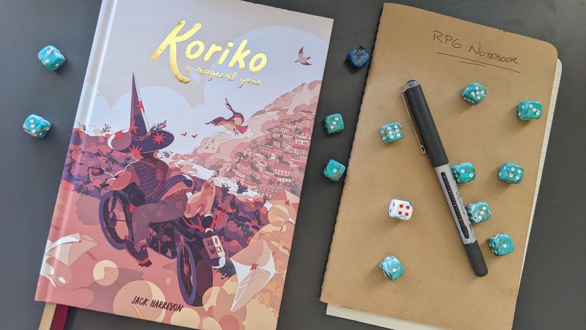 Koriko book on a dark green desk, along with a brown notebook, a black pen and a dozen or so d6 dice