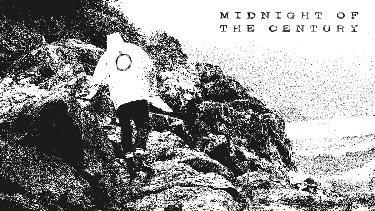 Moody black and white image of a person scrambling over a rocky coastline