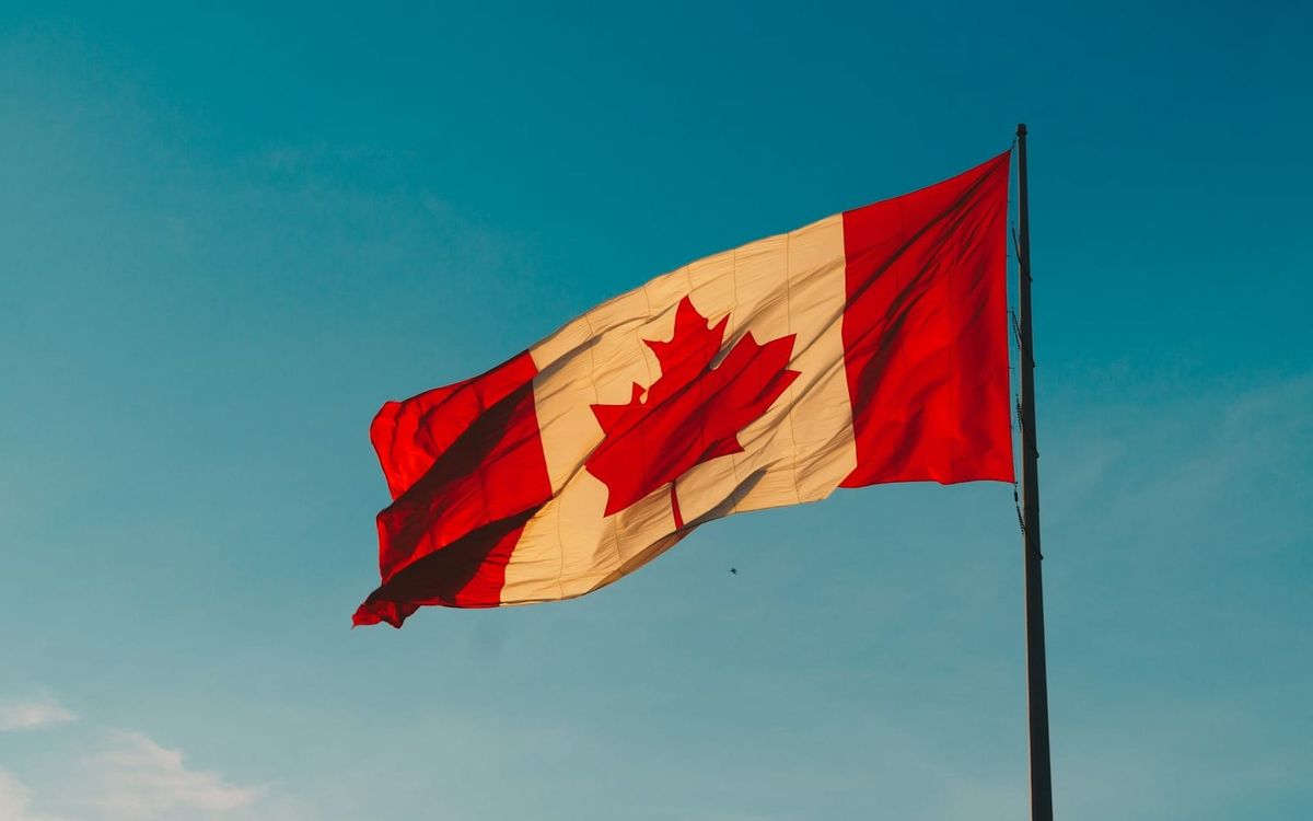 An image of a Canadian flag being flown on a pole.