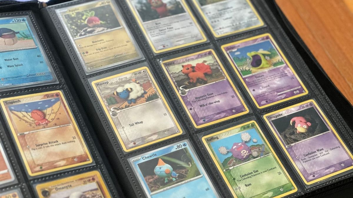 A black binder full of Pokémon cards sitting open on a wooden table.