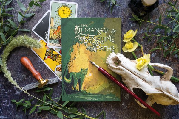 A softcover edition of The Almanac of Sanguine Paths on a dark stone background.