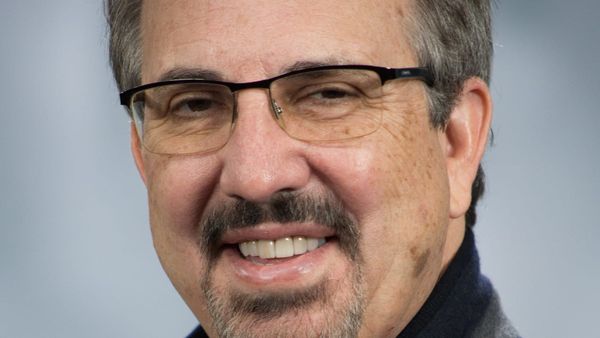 Photo of John Hight, smiling, on a grey-blue background