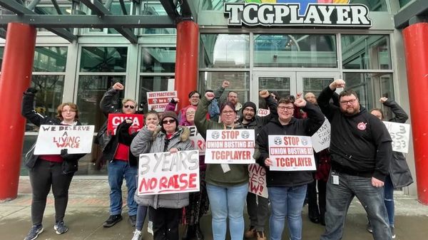 Over a dozen people picketing outside TCGPlayer offices. FIsts raise, many hold red and white signs with demands.