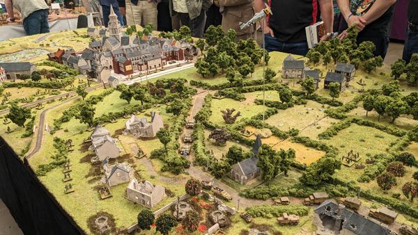 A photo of several people standing beside a large, beautifully crafted historical gaming board