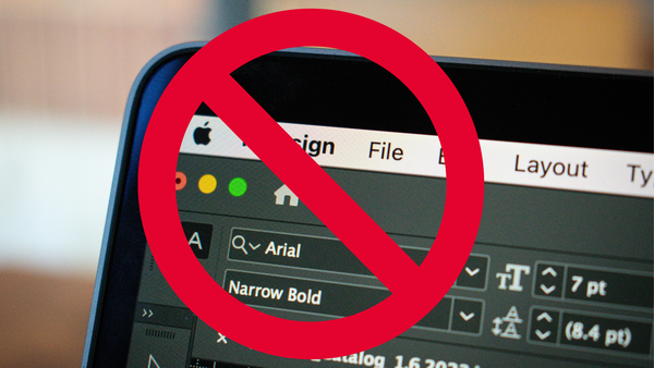 A red "no entry" sign, imposed on top of an image of Adobe InDesign used in a macbook.