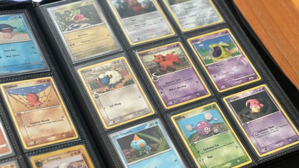 A black binder full of Pokémon cards sitting open on a wooden table.