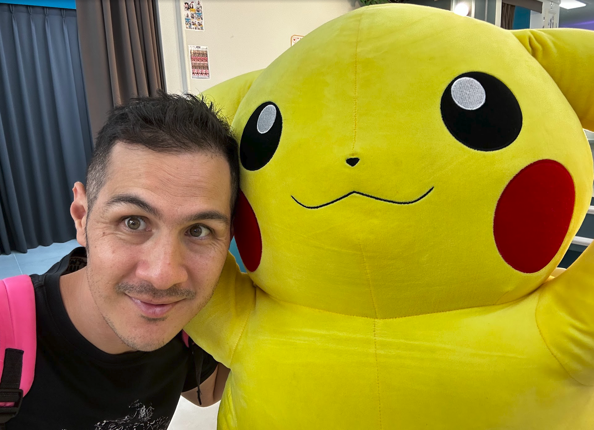 Darren taking a selfie beside a giant Pikachu plushie