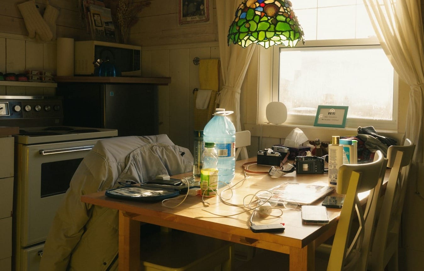 A cluttered kitchen table with a window