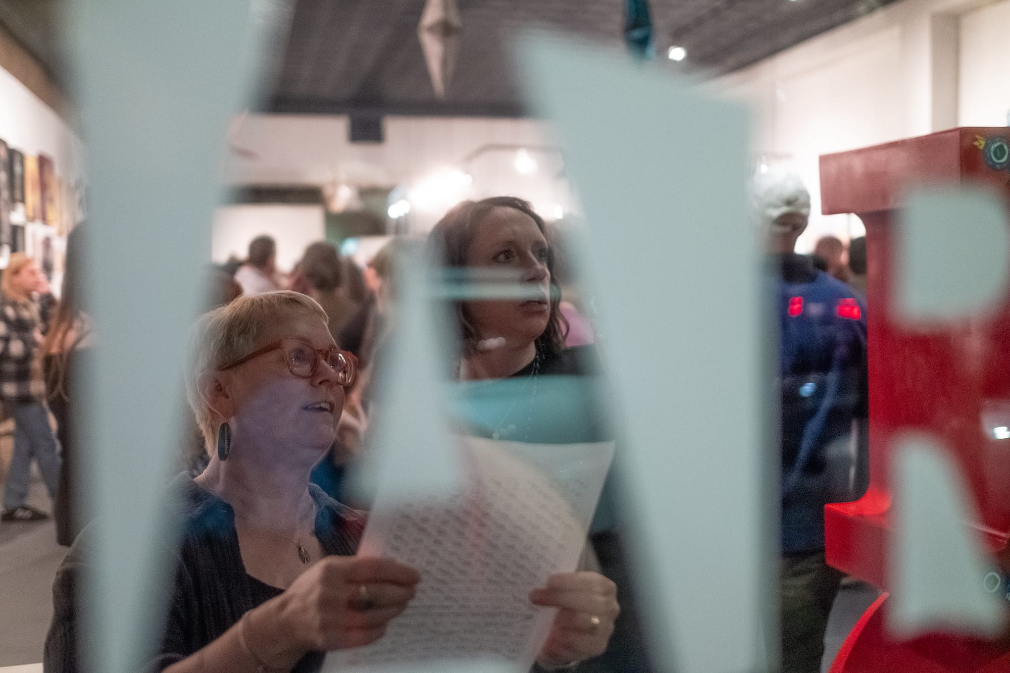 Two women peruse art.