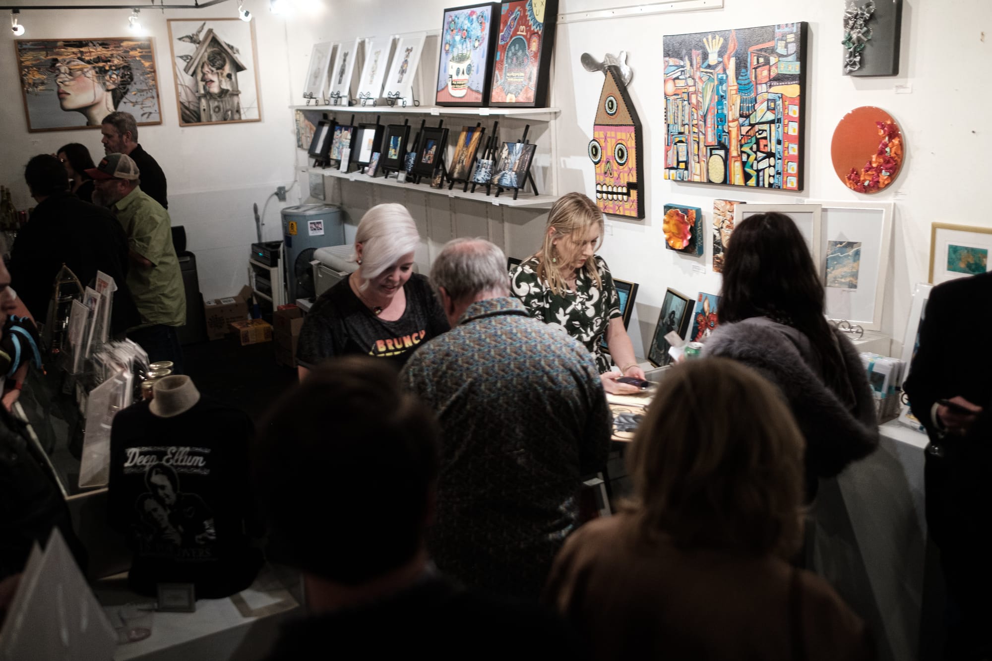 A crowd of art patrons gather at a cashier at an art gallery in Dallas