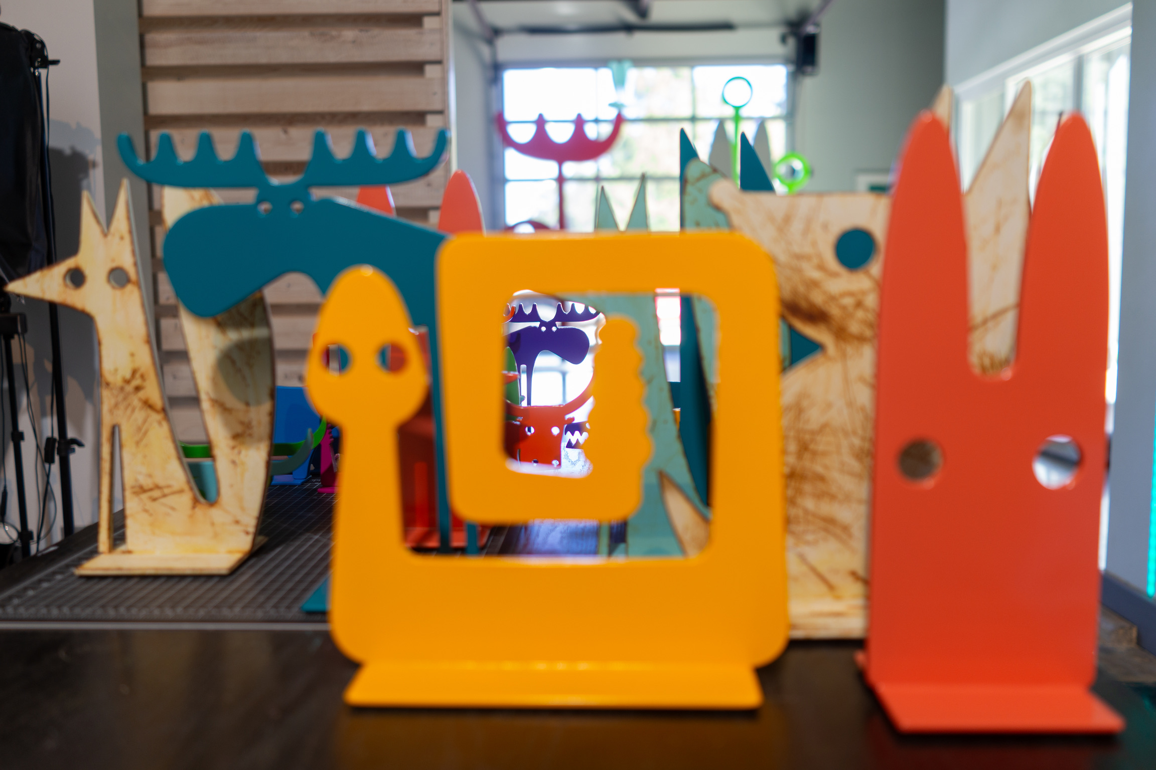 Blue moose, yellow snake and red bunny metal sculptures on a table.