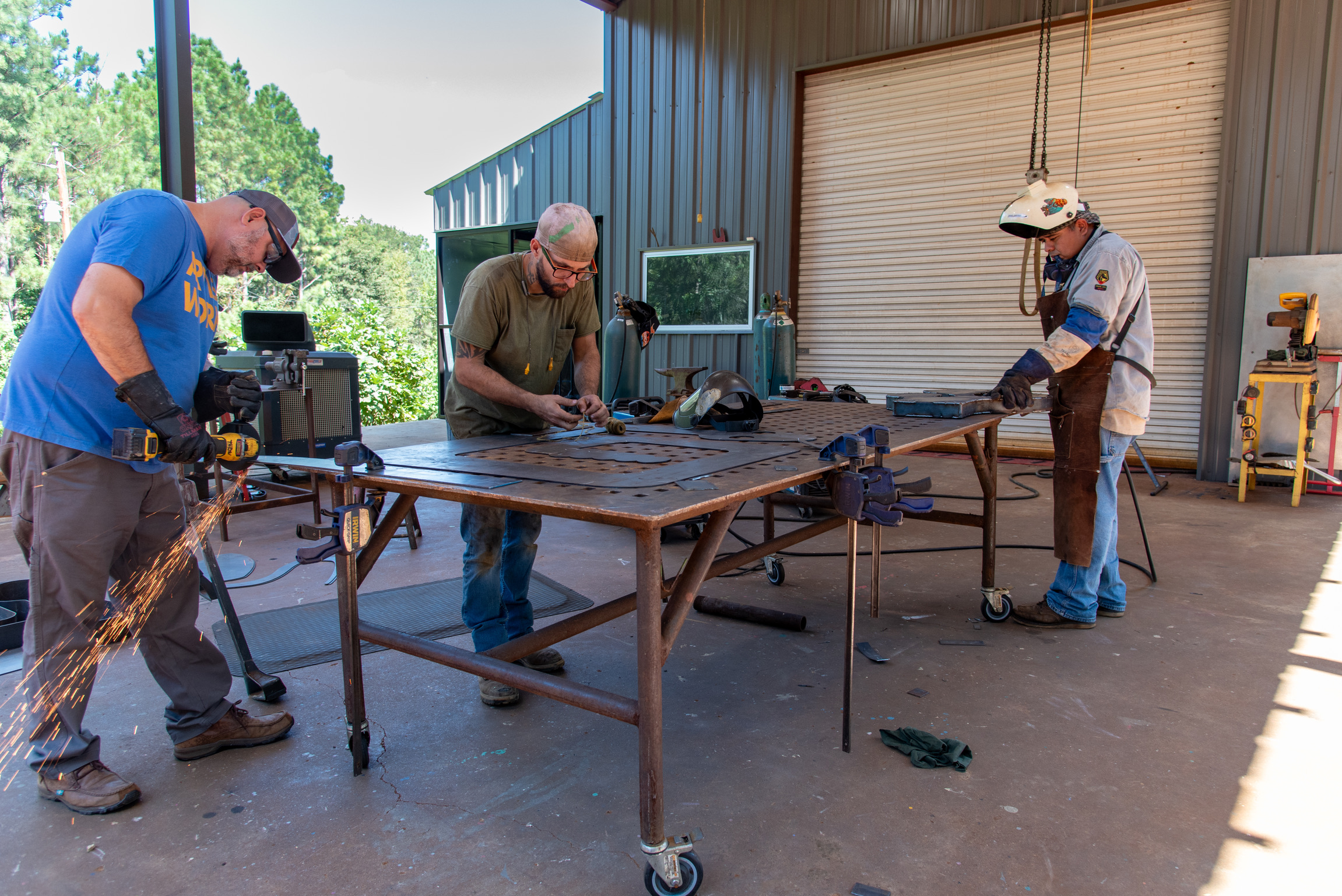 Jeffie Brewer and two studio workers shape a metal snake.