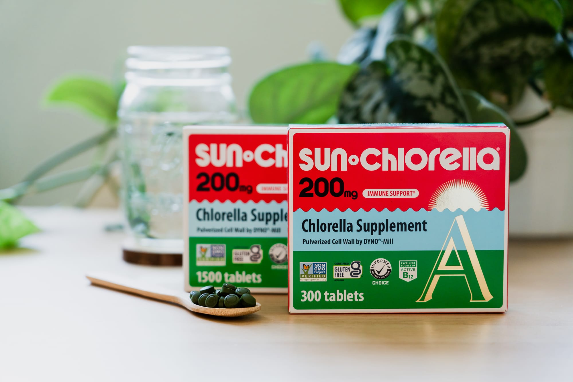 Boxes of Sun Chlorella tablets on wood surface with spoonful of chlorella tablets