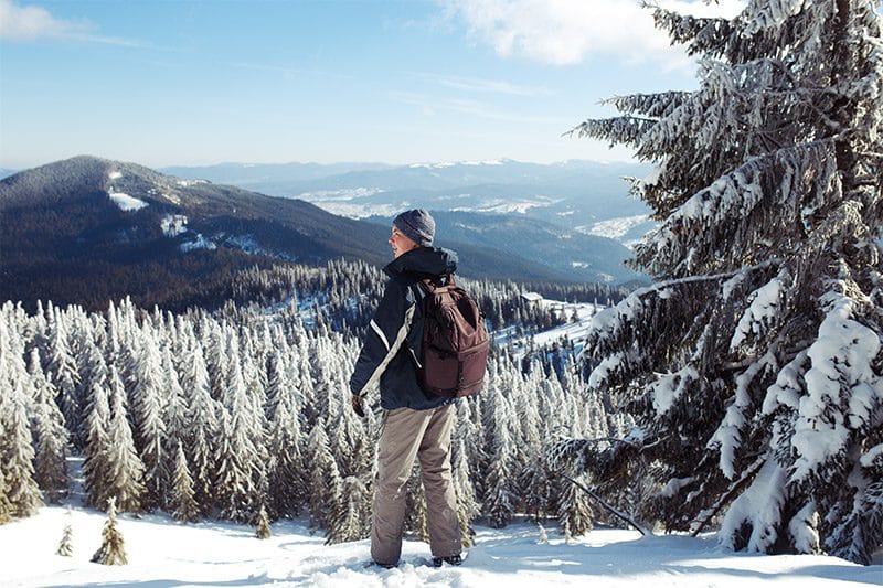 Person genießt den Ausblick auf eine verschneite Berglandschaft.
