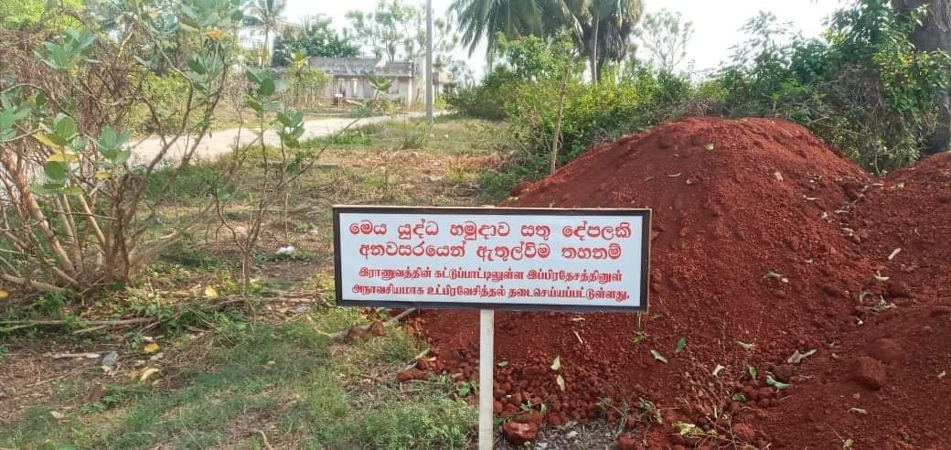 A military signboard in Sinhala and Tamil warns against entering restricted land in northern Sri Lanka, including privately owned Tamil property whose legal owners remain barred from access years after the civil war ended.