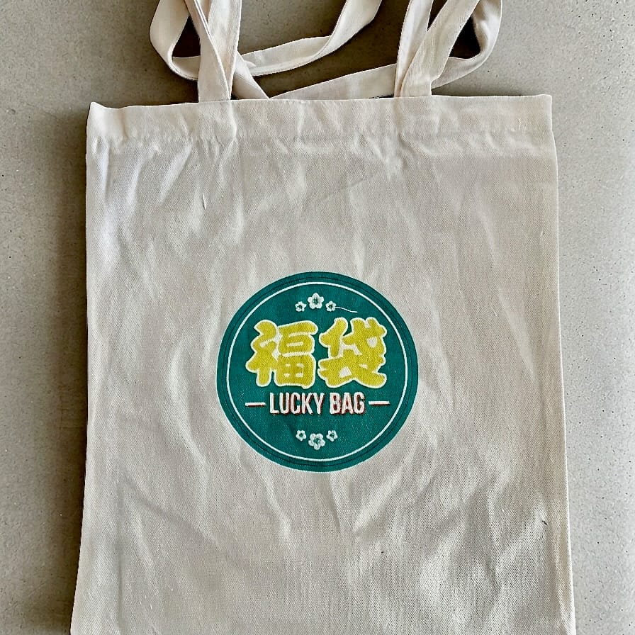 Tote bag en toile beige du Lucky Bag du Petit Vapoteur, avec logo 福袋 Lucky Bag.