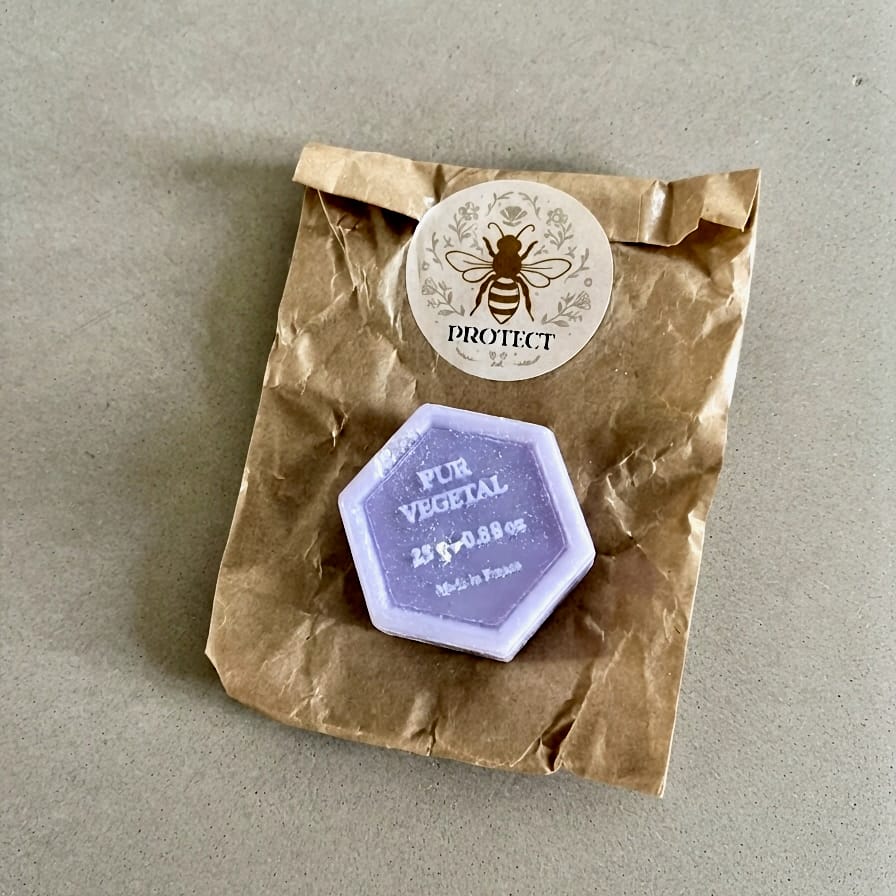 Savon hexagonal violet Pur Végétal posé sur son sachet kraft Protect décoré d'une abeille.