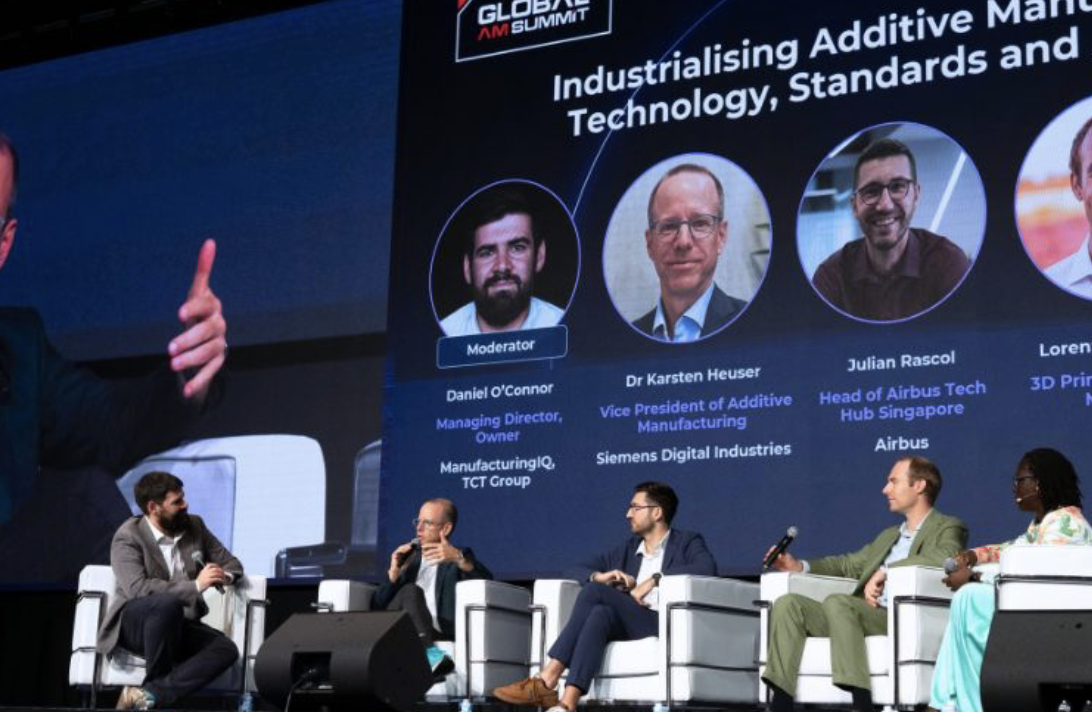 Five panellists on stage in front of a screen listing the speakers at the Industrialising Additive Manufacturing session, GAMS 2026, Singapore