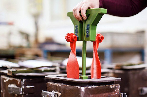 The 3D printed PLA plastic parts are attached to a wax frame and placed inside a container.