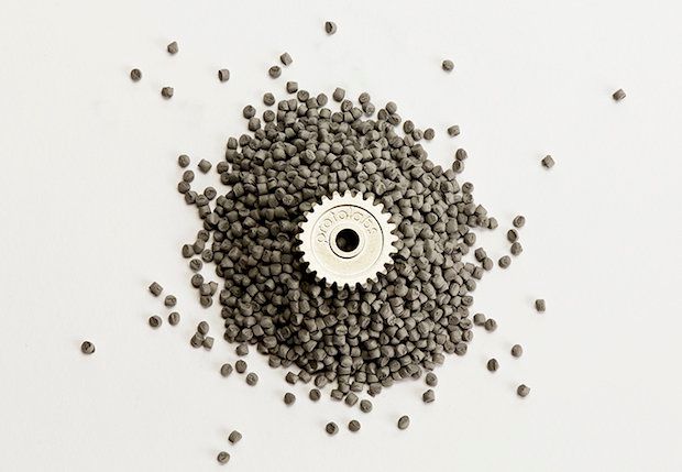 Fully dense component produced by metal injection moulding sits atop metal feedstock.
